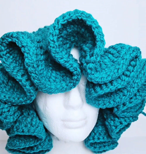 Close-up of The Angela teal crochet ruffle hat on a mannequin